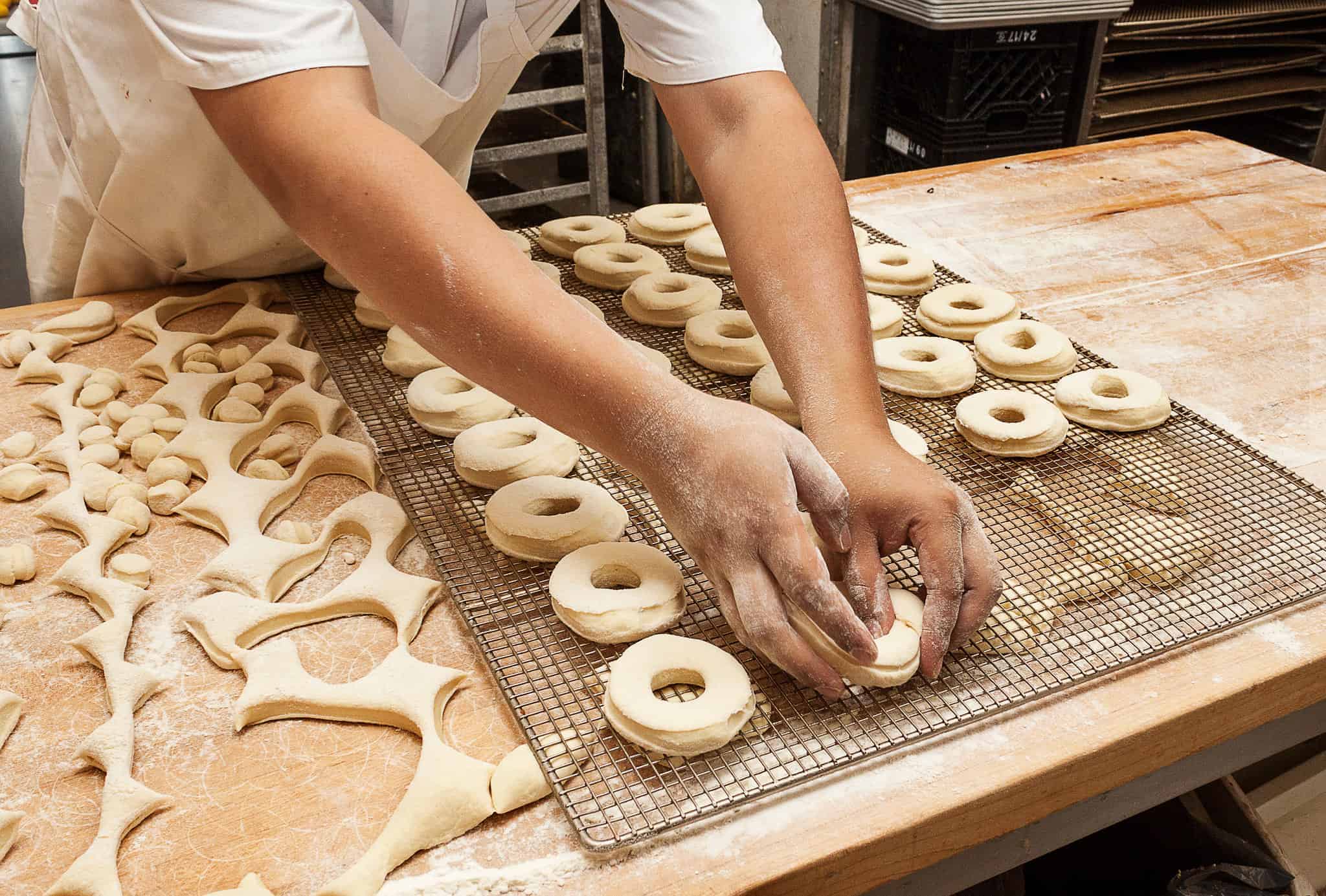Close up of man making donuts, placing the raw dough on a baking sheet